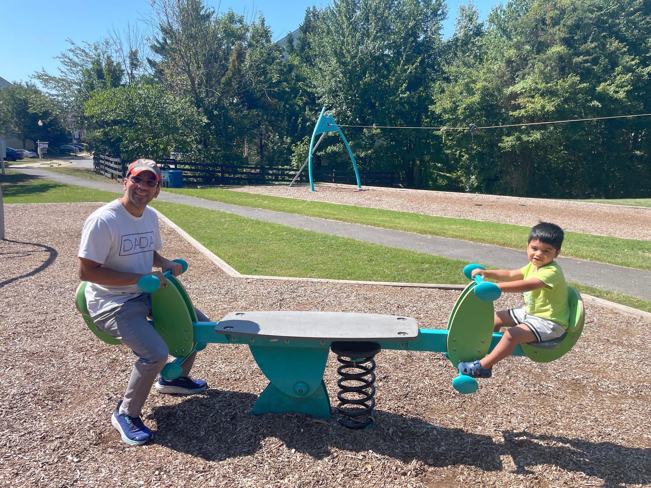Avinash and his son on a seesaw at the playground